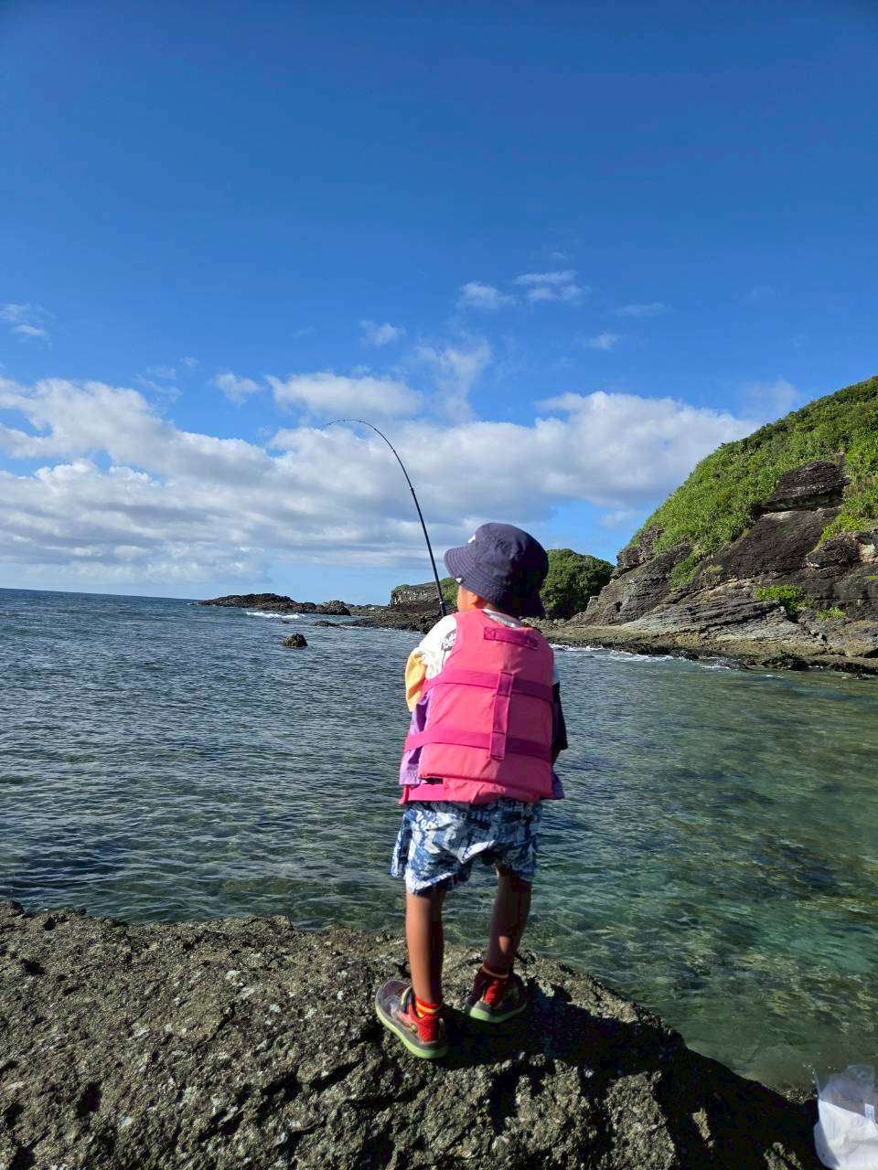 石垣島 穿著救生衣在岩場釣魚的少年背影｜浜ちゃん觀光